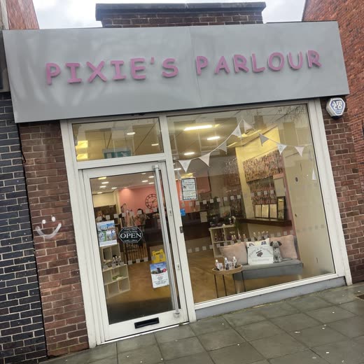 The salon's lit window display, cropped tight on the bunting and display so the fascia lettering is out of frame